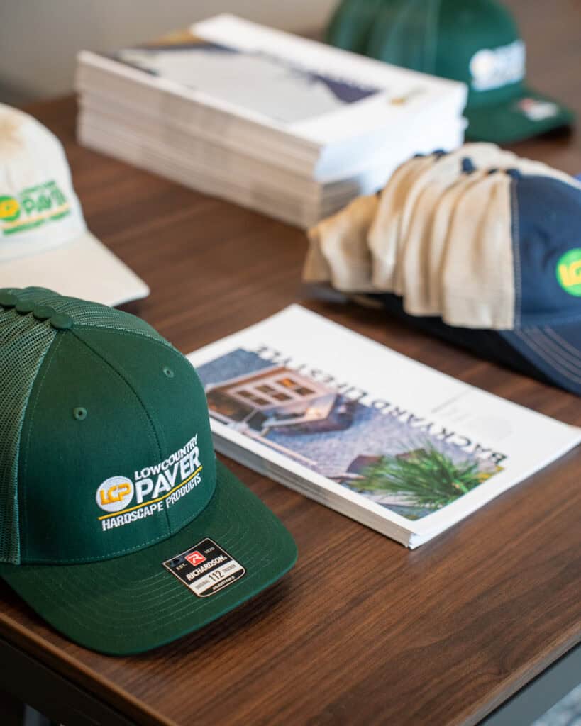 High-quality Lowcountry Paver cap, brochures, and promotional materials on a wooden table, showcasing professional landscaping products and branding for outdoor paving projects.