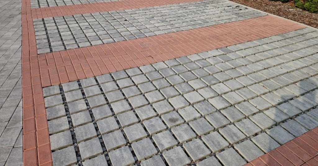 A large set of concrete permeable pavers installed outside. The gray permeable pavers are surrounded by red pavers