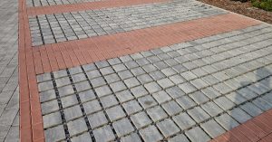 A large set of concrete permeable pavers installed outside. The gray permeable pavers are surrounded by red pavers