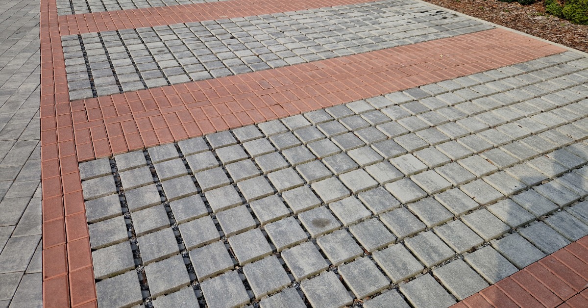 A large set of concrete permeable pavers installed outside. The gray permeable pavers are surrounded by red pavers